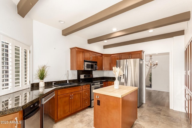 kitchen with appliances with stainless steel finishes, a center island, beam ceiling, a sink, and a chandelier