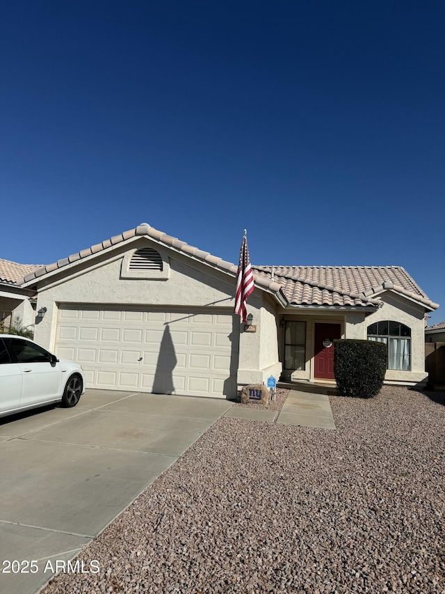 ranch-style home featuring stucco siding, an attached garage, driveway, and a tiled roof