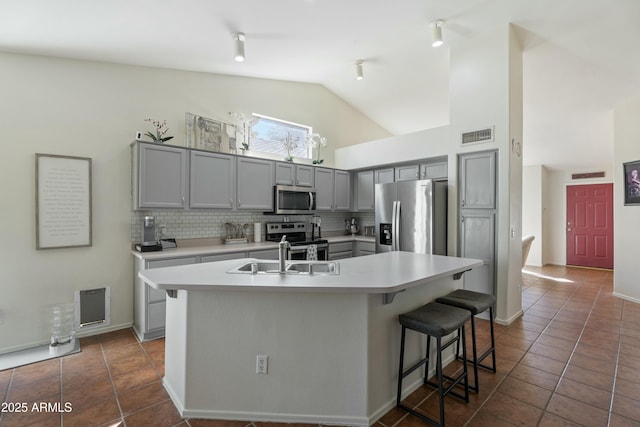 kitchen with a sink, gray cabinetry, backsplash, and stainless steel appliances