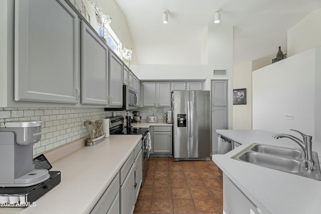 kitchen with decorative backsplash, appliances with stainless steel finishes, light countertops, and a sink