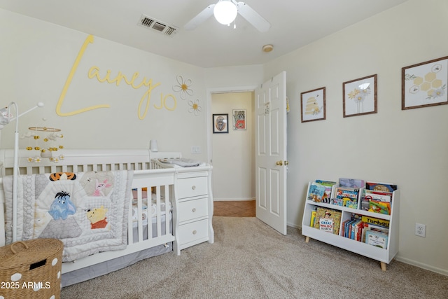 carpeted bedroom with a nursery area, baseboards, visible vents, and ceiling fan