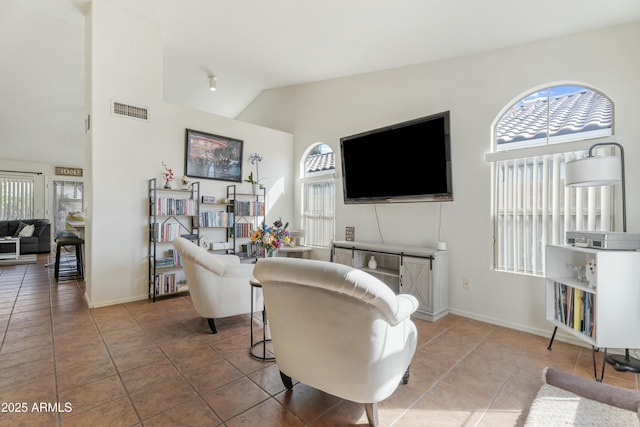 living area with visible vents, lofted ceiling, baseboards, and light tile patterned flooring