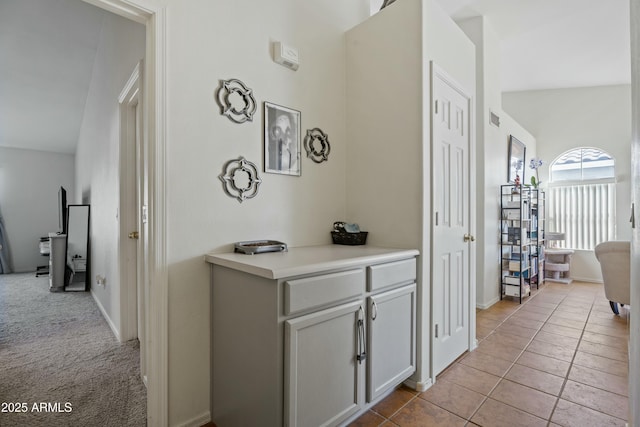 corridor with light tile patterned flooring, visible vents, light carpet, and baseboards