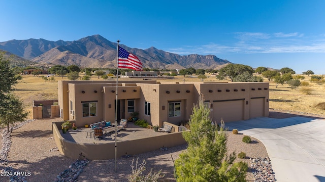 southwest-style home with a mountain view, a patio, and a garage