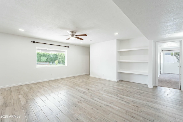 3743 E Coronado Rd, Phoenix, AZ 85008 - unfurnished living room featuring a textured ceiling, baseboards, a ceiling fan, and light wood-style floors
