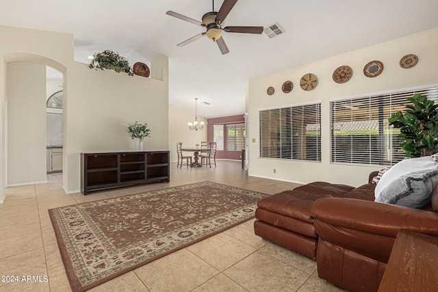 tiled living room featuring lofted ceiling and ceiling fan with notable chandelier