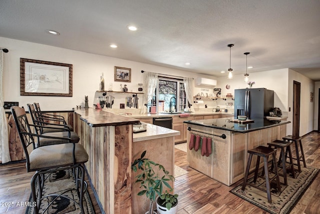 8894 W Lufkin Dr, Pine, AZ 85544 - kitchen featuring a kitchen bar, a wall mounted AC, stainless steel fridge with ice dispenser, a peninsula, and wood finished floors