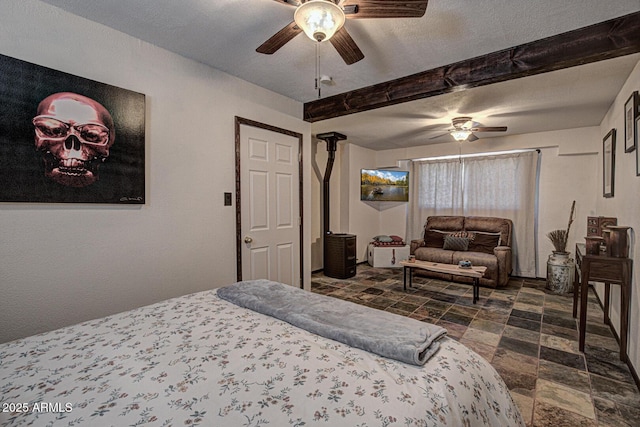 8894 W Lufkin Dr, Pine, AZ 85544 - bedroom with dark stone finish floors, beam ceiling, ceiling fan, and a wood stove