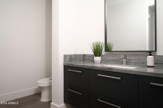 bathroom with hardwood / wood-style flooring, vanity, and toilet