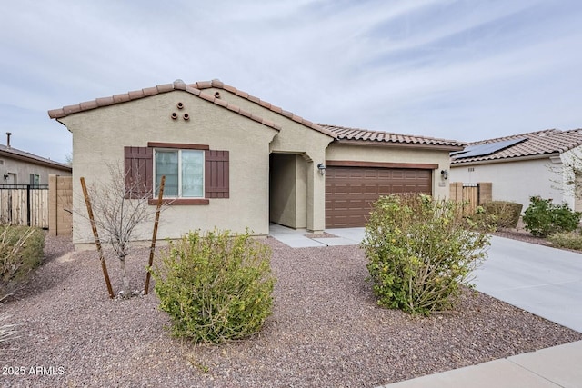 mediterranean / spanish home featuring stucco siding, concrete driveway, an attached garage, fence, and a tiled roof