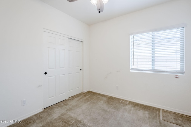 unfurnished bedroom with light carpet, a ceiling fan, baseboards, and a closet