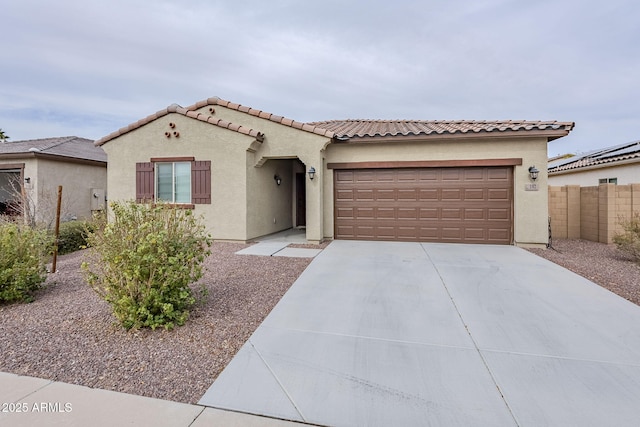 mediterranean / spanish-style house with driveway, a garage, a tile roof, fence, and stucco siding