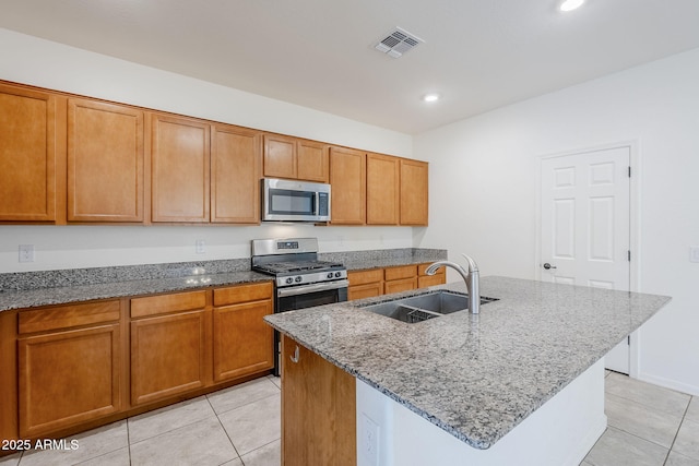 kitchen featuring visible vents, appliances with stainless steel finishes, a sink, and a center island with sink