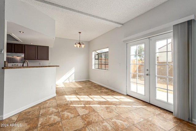 unfurnished dining area with french doors, a textured ceiling, a chandelier, sink, and light tile patterned floors