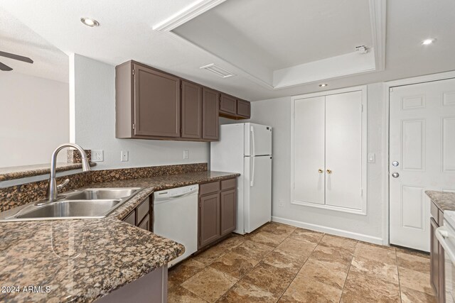 kitchen featuring white appliances, dark brown cabinetry, sink, a tray ceiling, and ceiling fan