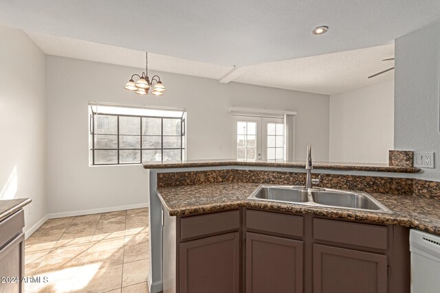 kitchen with sink, a textured ceiling, an inviting chandelier, decorative light fixtures, and dishwasher