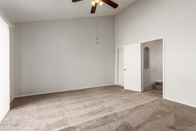 carpeted empty room featuring ceiling fan, a textured ceiling, and high vaulted ceiling