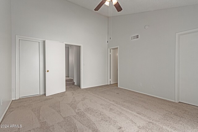 unfurnished bedroom featuring ceiling fan, a textured ceiling, light carpet, and high vaulted ceiling