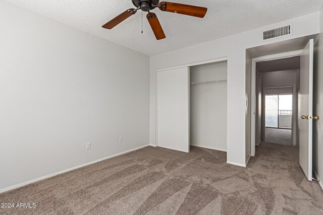 unfurnished bedroom with a textured ceiling, light carpet, ceiling fan, and a closet