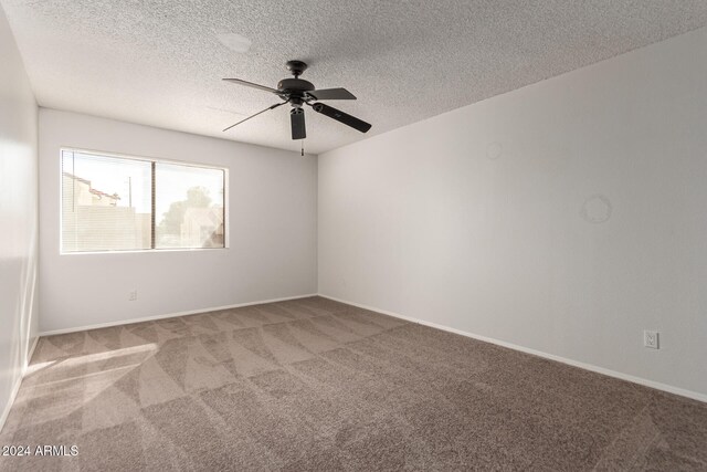 spare room with a textured ceiling, light colored carpet, and ceiling fan