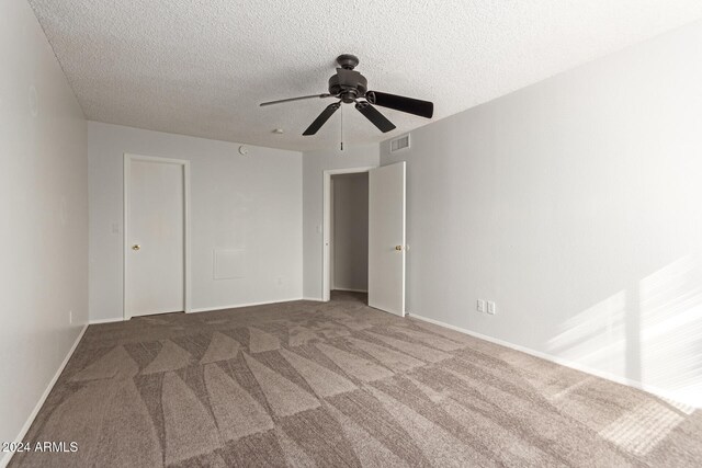 empty room featuring ceiling fan, a textured ceiling, and carpet floors