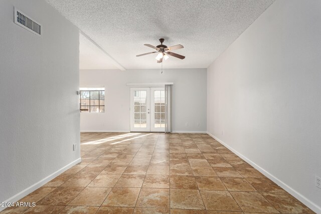 spare room featuring a textured ceiling, ceiling fan, and french doors