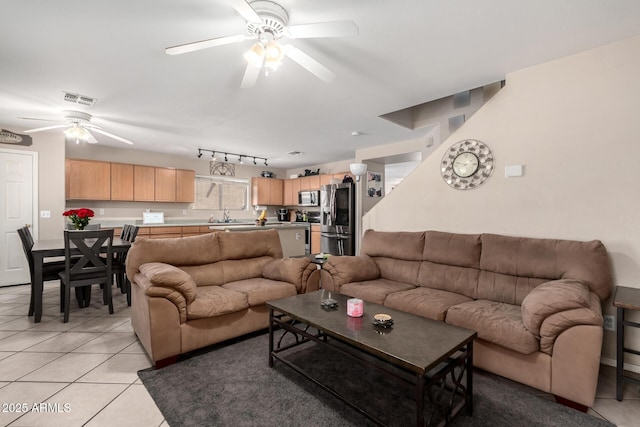 living area with ceiling fan, visible vents, and light tile patterned floors