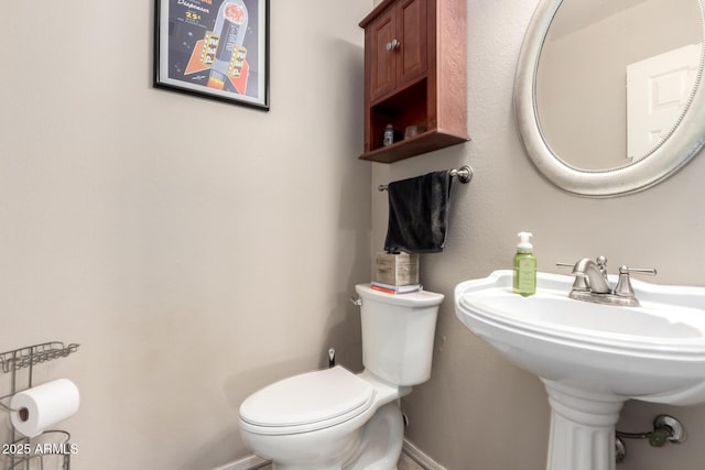 half bathroom featuring baseboards and toilet