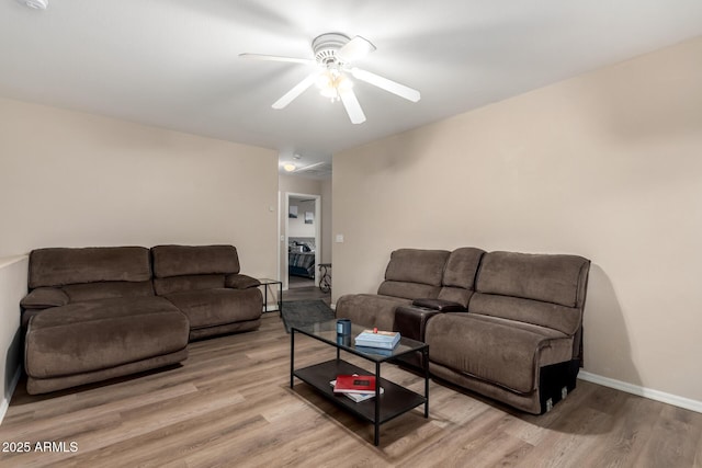 living room with light wood finished floors, baseboards, and a ceiling fan