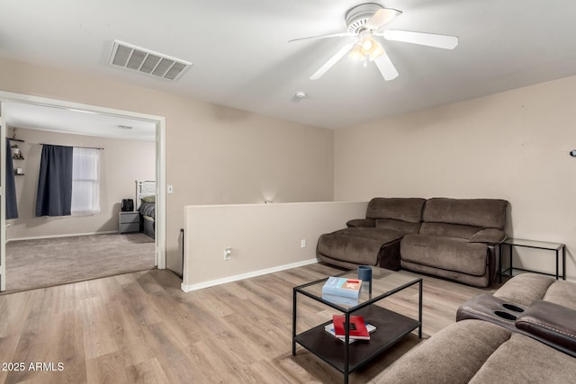 living area featuring light wood-style flooring, baseboards, ceiling fan, and visible vents