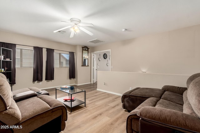 living room with baseboards, visible vents, light wood-style floors, and a ceiling fan
