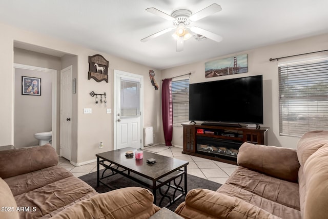 living area featuring a ceiling fan, light tile patterned floors, radiator, and baseboards