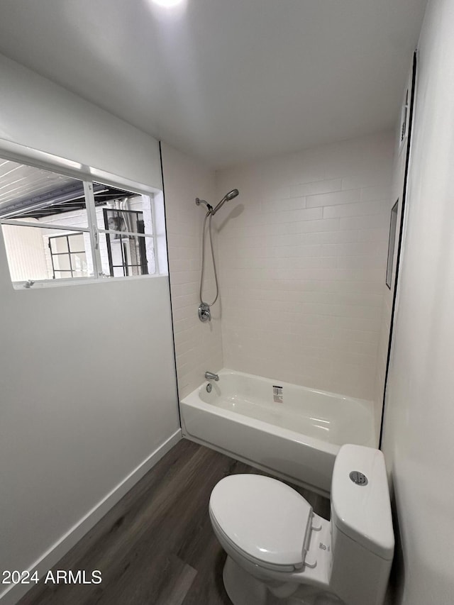 bathroom with tiled shower / bath combo, hardwood / wood-style flooring, and toilet