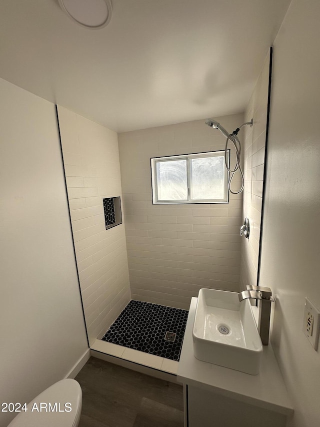 bathroom with a tile shower, sink, and toilet