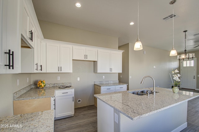 kitchen with white cabinetry, light stone countertops, sink, and a kitchen island with sink