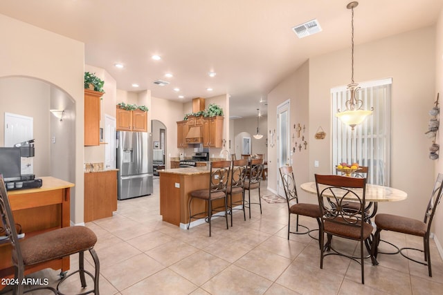 kitchen featuring light tile patterned floors, appliances with stainless steel finishes, light stone countertops, custom range hood, and kitchen peninsula