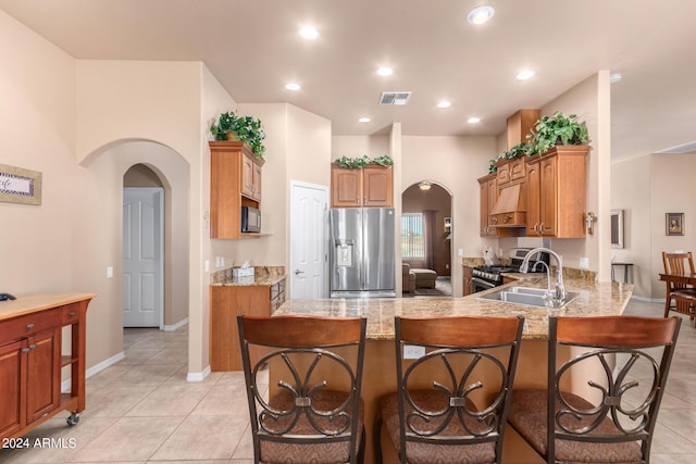 kitchen featuring appliances with stainless steel finishes, sink, custom exhaust hood, light tile patterned floors, and kitchen peninsula