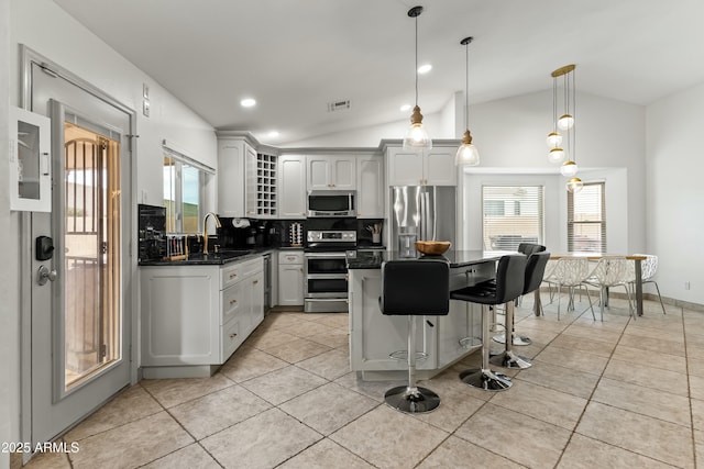 kitchen featuring appliances with stainless steel finishes, backsplash, sink, hanging light fixtures, and lofted ceiling