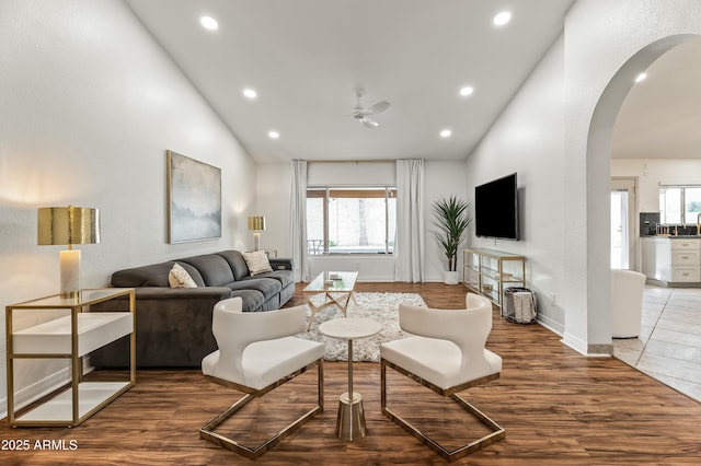 living room with ceiling fan, high vaulted ceiling, and wood-type flooring