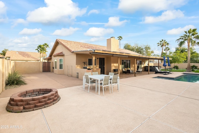 back of house with a fire pit, a fenced in pool, and a patio