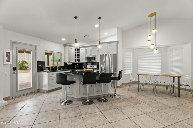 kitchen with sink, hanging light fixtures, vaulted ceiling, white cabinetry, and stainless steel appliances