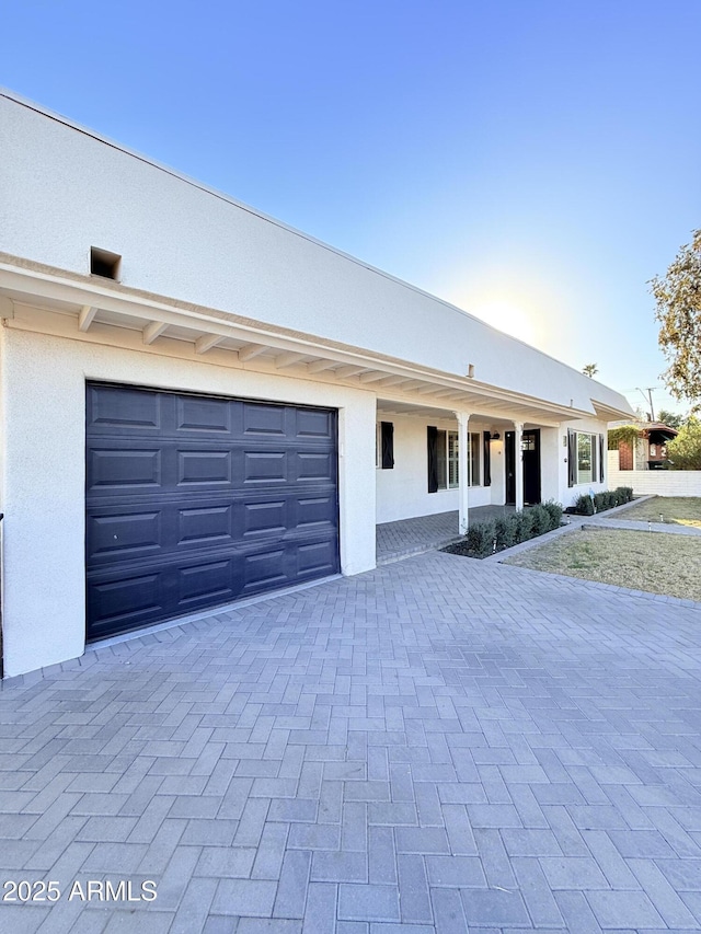 view of front of property with a garage, decorative driveway, and stucco siding