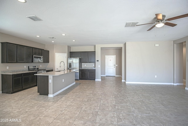 kitchen featuring light stone countertops, a kitchen island with sink, visible vents, and stainless steel appliances