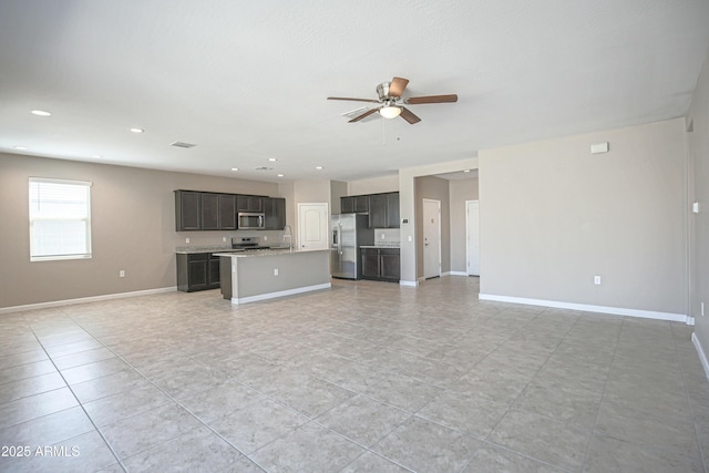 unfurnished living room featuring ceiling fan, recessed lighting, a sink, and baseboards