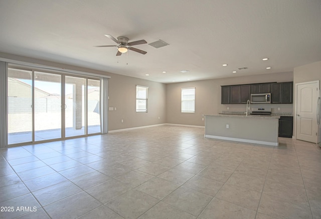 unfurnished living room featuring light tile patterned floors, recessed lighting, a ceiling fan, a sink, and baseboards