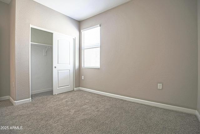 unfurnished bedroom with a closet, carpet flooring, a textured wall, and baseboards