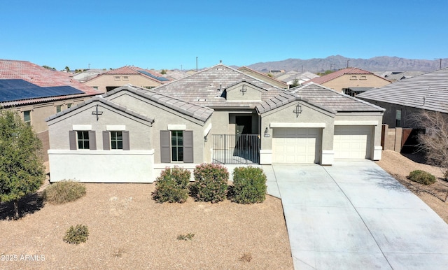 view of front of home with stucco siding, concrete driveway, a mountain view, a garage, and a residential view