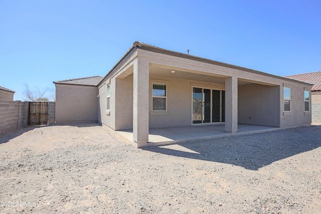 rear view of property with a patio area, a tiled roof, fence, and stucco siding