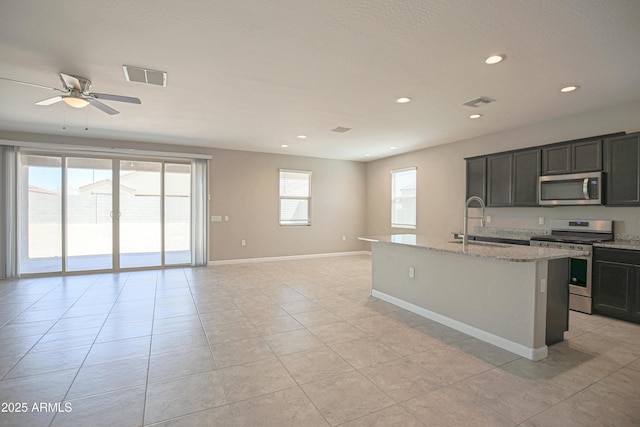 kitchen with visible vents, light stone counters, open floor plan, stainless steel appliances, and a sink