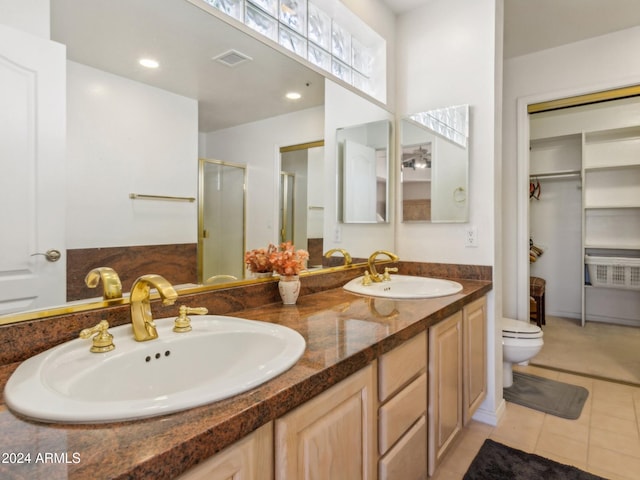 bathroom with tile patterned floors, vanity, a shower with shower door, and toilet